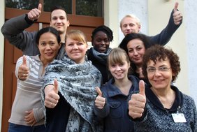 Glücklicher Umzug (Krankenhaus Barmherzige Brüder Regensburg) Auf dem Foto sind viele glückliche Leute zu sehen, in unterschiedlichen hautfarben, die alle den Daumen nach oben zeigen.