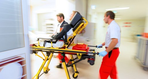 zwei Sanitäter bringen gerade einen Patienten auf der Liege ins Notfallzentrum.