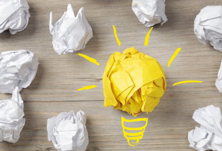 Eine Birne und Papierbälle stehen für "Idee, Konzept"