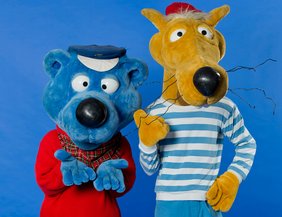 Käptn Blaubär (Krankenhaus Barmherzige Brüder Regensburg) Auf dem Foto sieht man links Käpt'n Blaubär, das ist ein Mensch der ein blaues Plüschkostum mit Matrosenmütze und rotem Tshirt trägt. Rechts sieht man Hein Blöd, eine Art Giraffe mit blau weißem Streifenoberteil und roter Mütze.