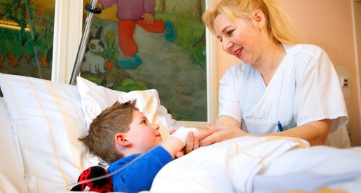Eine Kinderkrankenschwester kümmert sich auf Station um einen kranken Jungen.